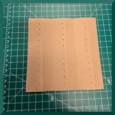 Photo of a piece of cardboard with three lines of holes