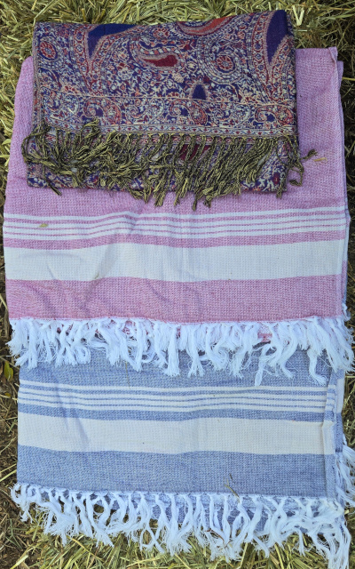 Photo of three folded piles of fabric lying on a hay bale