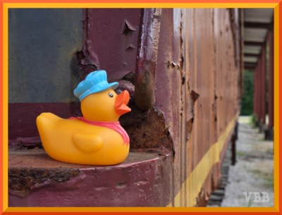 photo of yellow rubber duck sitting on old railroad car