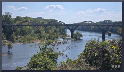 photo of a bridge with multiple arches crossing a river with greenery on both banks