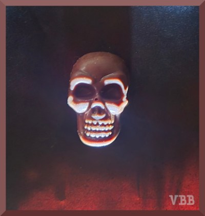 photo of a chocolate skull on black paper, with dramatic uplighting