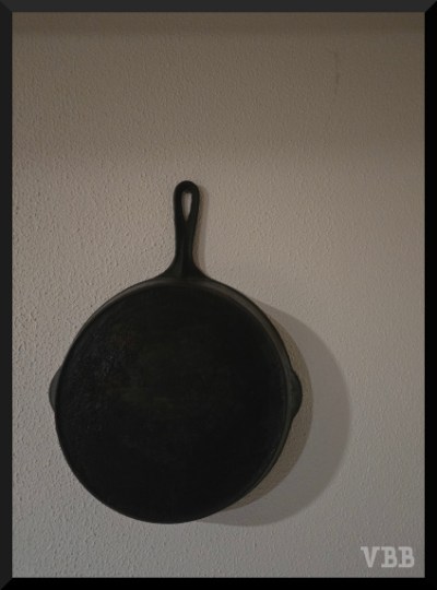 photo of black frying pan hanging on white wall