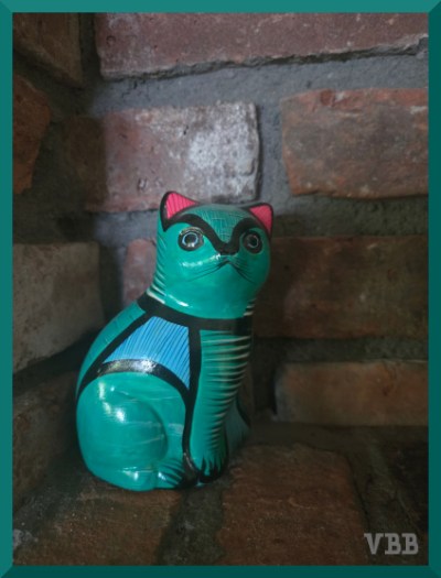 photo of small green cat statue in brick alcove