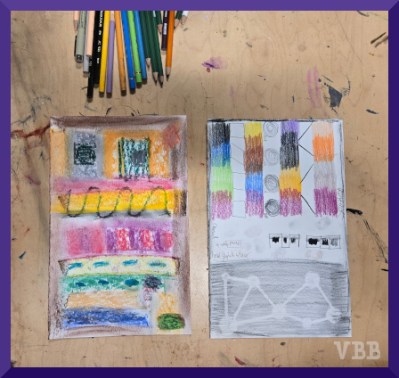 photo of colored pencils and two artworks resting on a table