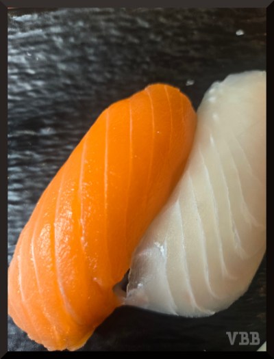 photo of two pieces of sushi on a dark plate