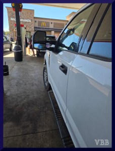 photo of the side of a white truck at a gas station