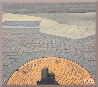 Photo of two crossed feet on a city sidewalk