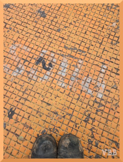 Photo of the front of two boots on an orange manhole cover