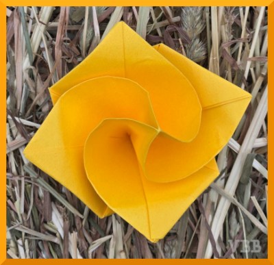 Photo of a yellow origami rose sitting on hay