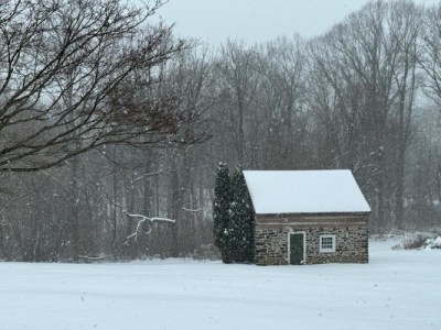 Photo of stone cabin with trees in falling snow