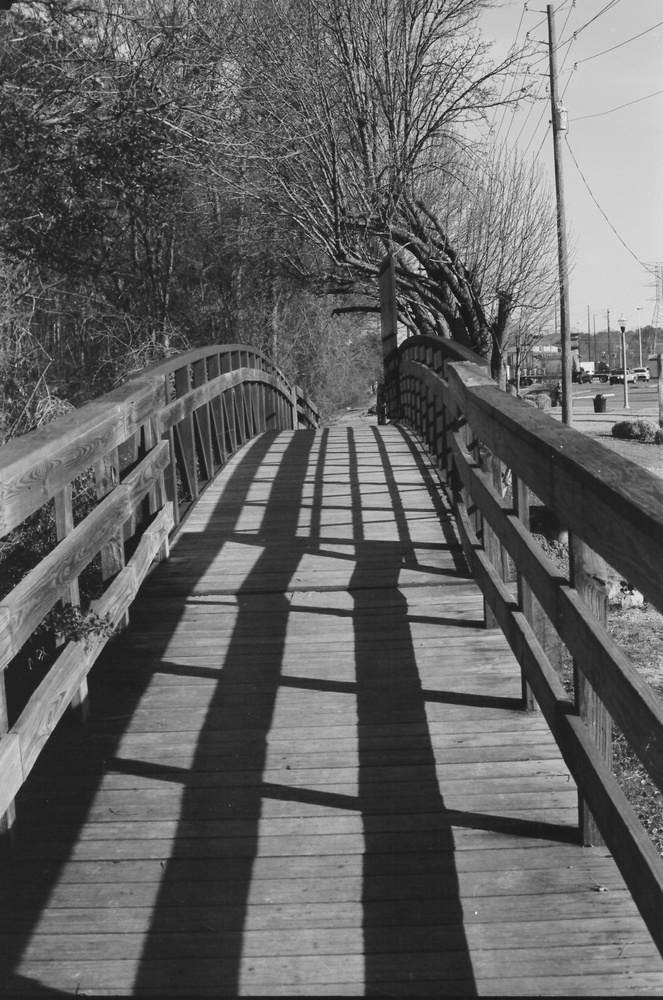 Black and white photo of a wooden bridge with shadows.