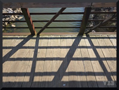 Photo of part of a bridge with shadows of the handrail on the walkway