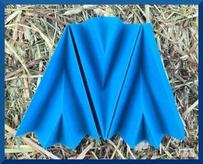 Photo of three sheets of blue paper folded into pleated arrows and set in a row