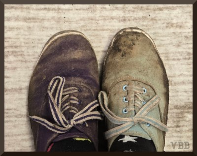 Photo of a mismatched pair of muddy sneakers.