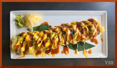 Photo of a sushi roll with sauce on a white tray