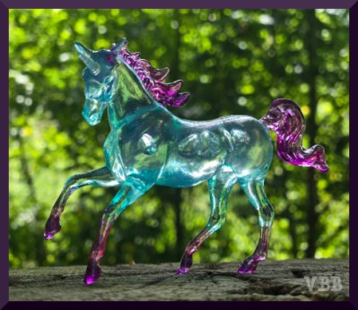 Photo of a transparent plastic model on a wooden surface with trees in the background