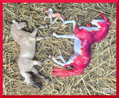 Photo of three model horses lying on hay.