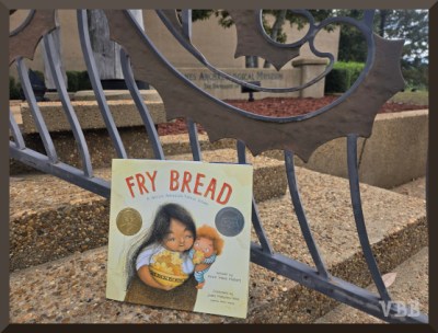 Photo of the book Fry Bread resting on the steps of the Jones Archeological Museum.
